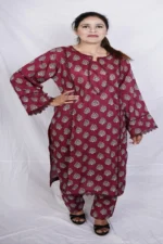 Woman posing with hand on hip in a maroon kurta design for women with white print and lace sleeves, paired with matching salwar.